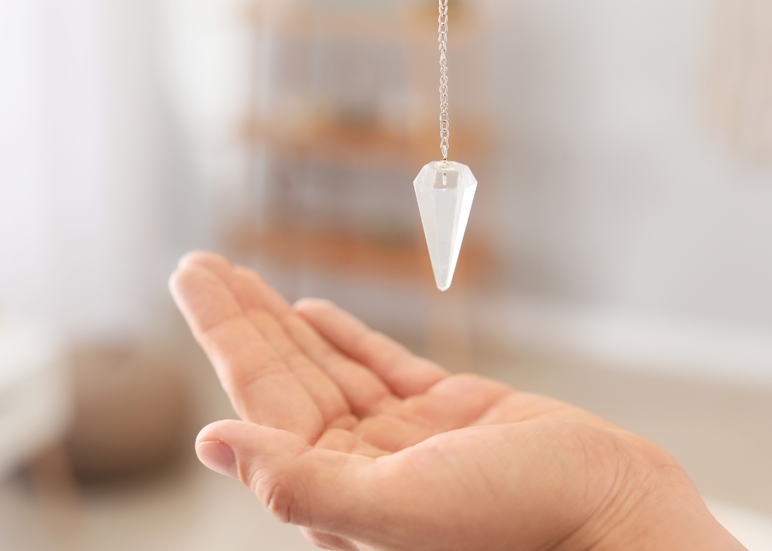 Crystal pendulum held above an open hand