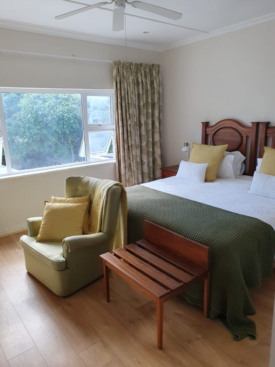 Hibiscus Suite king bed and armchair beside a garden-view window