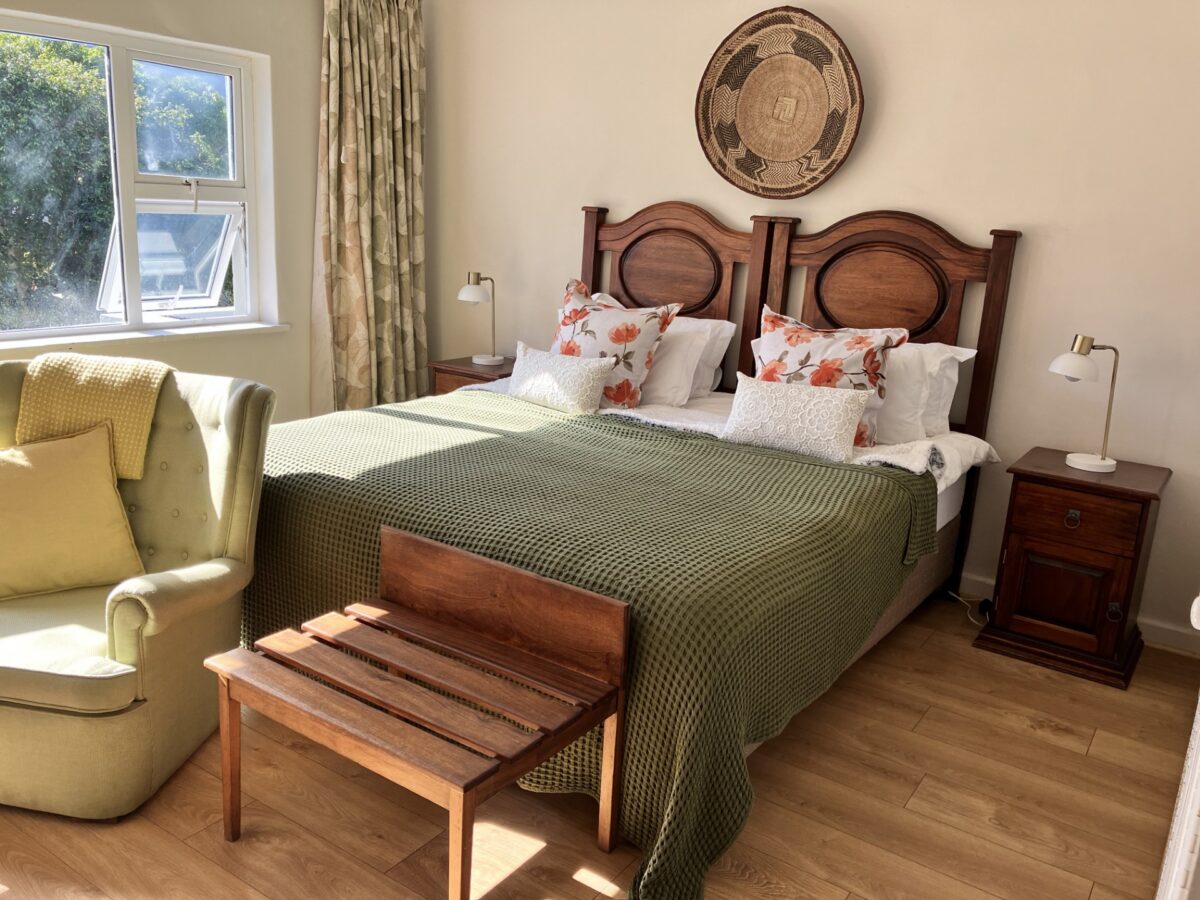Hibiscus Suite king bed with green throw and bedside lamps